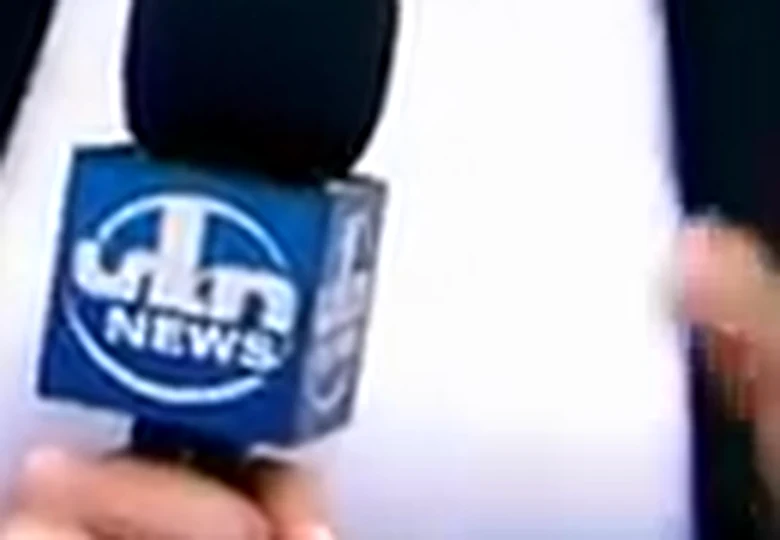 Close crop of the microphone flag showing the word NEWS below a circular emblem with letterforms that do not spell a word